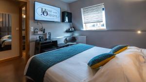 a bedroom with a bed and a desk and a television at Hôtel d'Orléans in Orléans