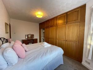Un dormitorio con una gran cama blanca con almohadas rosas. en 1930s 3Bed House in Quiet Village w/ Large Garden, en Bishopton 17 fotos más