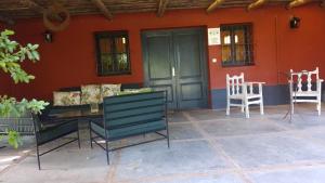 eine Terrasse mit 2 Stühlen, einem Tisch und einem Haus in der Unterkunft La Mancha Verde in Capitán Sarmiento