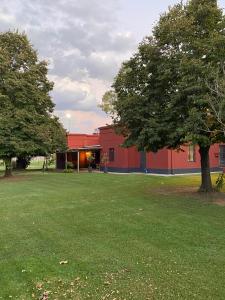 un edificio rojo con un árbol en medio de un campo en La Mancha Verde in 