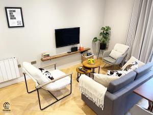 ein Wohnzimmer mit einem Sofa und Stühlen sowie einem Flachbild-TV in der Unterkunft Character filled Courtyard Escape in Harrogate
