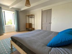 um quarto com uma cama com almofadas azuis em Maison à 500m de la plage em Plogoff