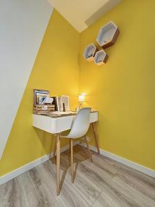 einen Schreibtisch mit einem Stuhl neben einer gelben Wand in der Unterkunft Confort, wifi et garage in Millau
