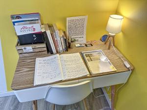einen Schreibtisch mit Büchern, einer Lampe und einem Stuhl in der Unterkunft Confort, wifi et garage in Millau
