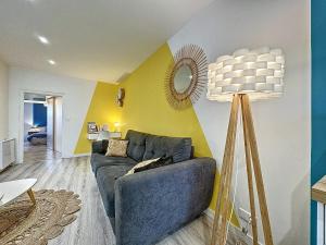 a living room with a blue couch and a yellow wall at Confort, wifi et garage in Millau