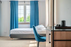 a bedroom with a bed and a blue chair at Przystań Jeziorany - Willa nad jeziorem z plażą jacuzzi i sauną na wyłączność in Jeziorany