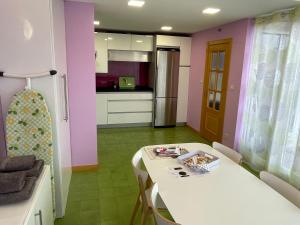 a room with a table and a kitchen with pink walls at Apartamento con gran terraza y vistas a la catedral. in Burgos