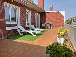 un patio con 2 sillas blancas y una mesa en Apartamento con gran terraza y vistas a la catedral., en Burgos