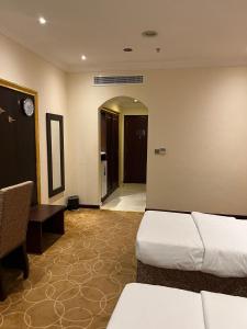 pokój hotelowy z 2 łóżkami i stołem oraz korytarzem w obiekcie فندق بنيان العزيزية w Mekce