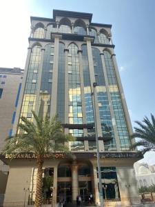 فندق بنيان العزيزية في مكة المكرمة: مبنى كبير أمامه أشجار نخيل