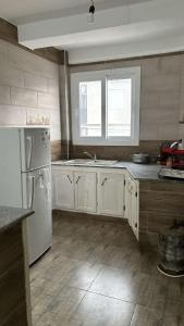 a kitchen with a white refrigerator and a window at Plage à 500 mètres! Appartement familial paisible avec vue sur mer à Melbou, idéal pour des vacances relaxantes. in Les Falaises