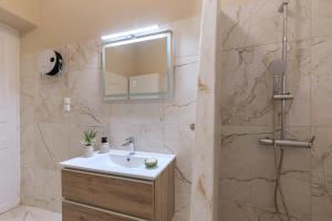 a bathroom with a sink and a shower with a mirror at Loukoumi in Ermoupoli +36 photos