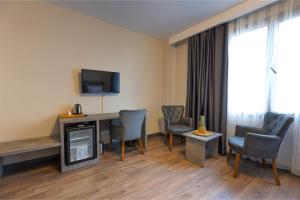 a hotel room with a desk and chairs and a television at GRANDROYAL HOTEL in Gümüşyaka