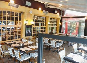 uma sala de jantar com mesas e cadeiras num restaurante em Les Cascades - Hôtel de Charme em Honfleur