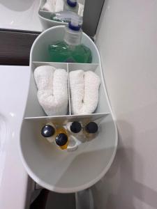 a shelf with three towels and a bottle of soap at Modern 2 Bedroom Flat in Quiet Village w/ Ensuite in Bishopton