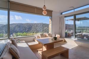 a living room with a table and a large window at Hidden Retreats Kythera in Platia Ammos