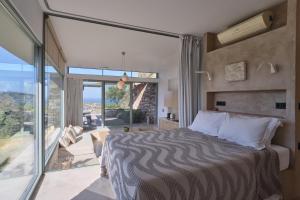 a bedroom with a bed and a large glass window at Hidden Retreats Kythera in Platia Ammos