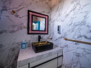 a bathroom with a sink and a marble wall at B&W SAHARA SKY CAMP in Qasr Al Farafirah