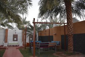 a patio with a table and chairs and a palm tree at منتجع ريف خزيمة - الفيروز in Medina