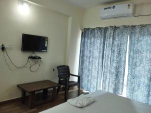 een slaapkamer met een bed, een stoel en een televisie bij Née Barsha residency in Puri