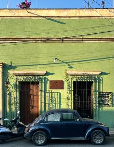une voiture bleue garée devant un bâtiment dans l'établissement Hostal Nordés, à Oaxaca
