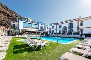a courtyard with chairs and a swimming pool at Billy's Puerto de Mogán Apartments by LIVVO in Puerto de Mogán