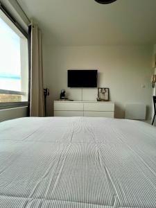 a bedroom with a white bed and a flat screen tv at L’Oliveraie in Lille +4 photos
