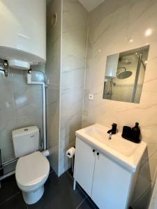 a bathroom with a white toilet and a sink at L’Oliveraie in Lille