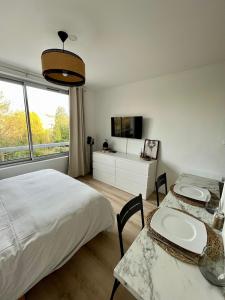 a bedroom with two beds and a table and a tv at L’Oliveraie in Lille