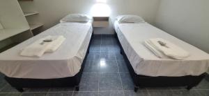 Dos camas en una habitación pequeña con toallas. en COMPLEJO TURISTICO RIOJA en La Rioja