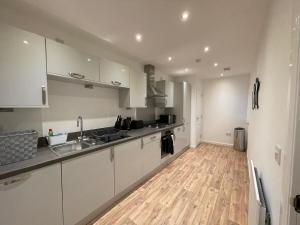 a kitchen with white cabinets and a wooden floor at 2 bedroom luxury flat in quiet village of Bishopton in Bishopton