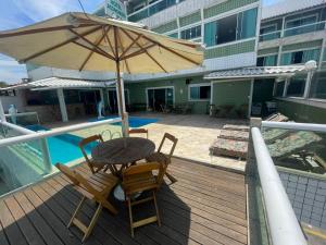 a wooden deck with a table and chairs and an umbrella at Hotel Aconchego Da Vila in Saquarema +117 photos