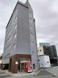 un edificio alto con una máquina de coca roja delante de él en FLYCAT INN 伊勢, en Ise