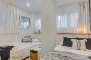 two beds in a room with white walls and windows at Super Centro y Playa by TheBlueWaveApartments com in A Coruña