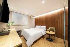 仁川にあるNo 25 Hotel Dongam Branchの白いベッドとテーブルが備わるホテルルームです。