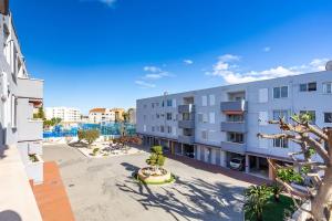 um edifício de apartamentos com uma árvore em primeiro plano em Javea Family Oasis: Steps from the Beach em Platja de l'Arenal