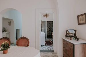 Ein weißes Zimmer mit einem Tisch und einem Badezimmer. in der Unterkunft Casa Del Tempio Antico, Salento in Arnesano