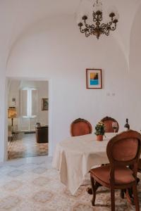 ein Esszimmer mit einem Tisch, Stühlen und einem Kronleuchter in der Unterkunft Casa Del Tempio Antico, Salento in Arnesano