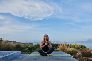 a woman is sitting on a yoga mat at Hidden Retreats Kythera in Platia Ammos