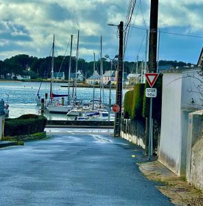 eine Straße neben einem Yachthafen mit Booten im Wasser in der Unterkunft Maison de pêcheur Etel in Étel