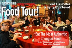 un grupo de personas sentadas alrededor de una mesa comiendo comida en Chengdu Mix Hostel Courtyard Poshpacker (Wenshu Monastery) en Chengdú