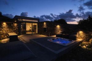 una casa con bañera de hidromasaje en un patio por la noche en Hidden Retreats Kythera en Platia Ammos