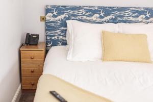 a bedroom with a bed and a phone on a night stand at The Salutation Inn in Topsham