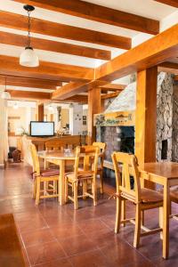 comedor con mesas y sillas de madera y chimenea en Hosteria y Cabañas Posada Quinen by Nordic en San Martín de los Andes