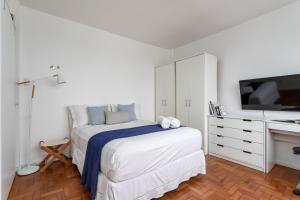 een witte slaapkamer met een bed en een televisie bij Unhotel - Perfeito Apartamento Temporada no Leblon, Perto da praia in Rio de Janeiro