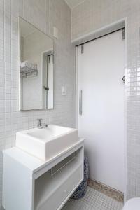 een witte badkamer met een wastafel en een spiegel bij Unhotel - Perfeito Apartamento Temporada no Leblon, Perto da praia in Rio de Janeiro