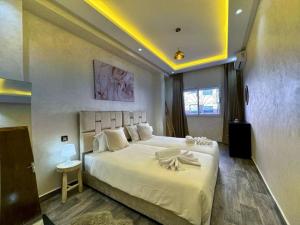 - une chambre avec un grand lit blanc et une fenêtre dans l'établissement Bel Appart Familial Majorelle, à Marrakech