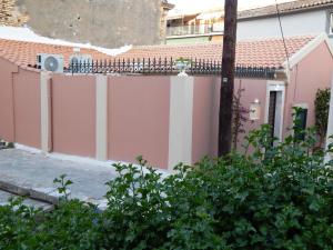 Sole Apartments - near Corfu Port في Ágios Rókkos: سياج وردي وبيضاء أمام المنزل