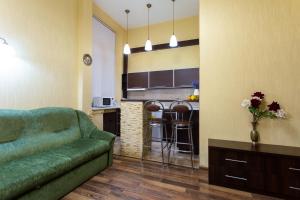 a living room with a green couch and a kitchen at Royal Apartment on Pushkinskaya in Kharkiv