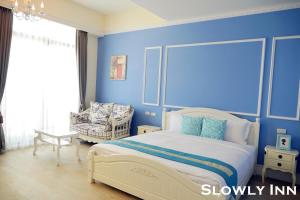 a blue bedroom with a bed and a chair at Slowly inn in Hengchun